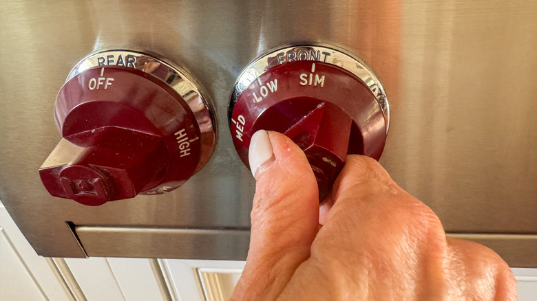 hand adjusting stove temperature