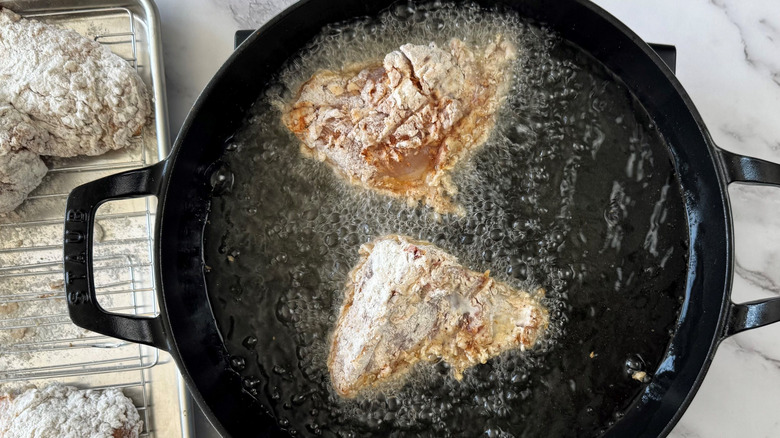 Chicken breasts frying in large skillet