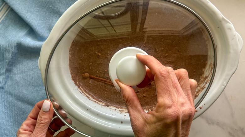 hand adding cover to slow cooker