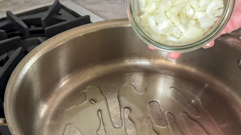 hand adding onion to pan