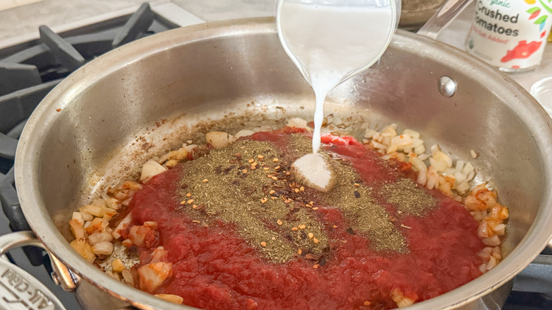 hand adding cream to pan
