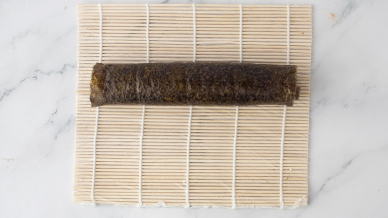 Rolled up sushi roll on bamboo mat