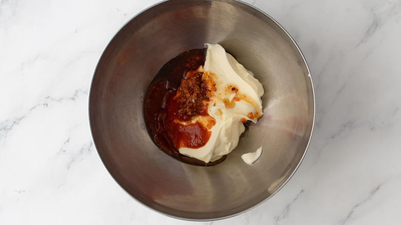Mayonnaise, sriracha, and chili crisp in mixing bowl