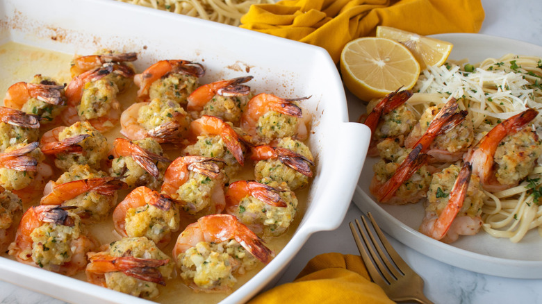 Stuffed shrimp scampi in casserole dish next to plate with scampi
