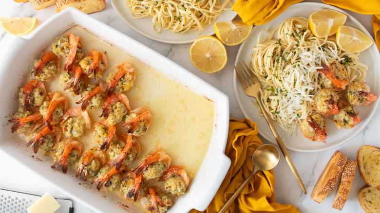 Stuffed shrimp scampi in baking dish next to scampi and pasta on plate