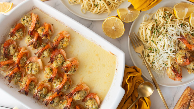 Stuffed shrimp scampi in casserole dish next to plate with scampi and pasta