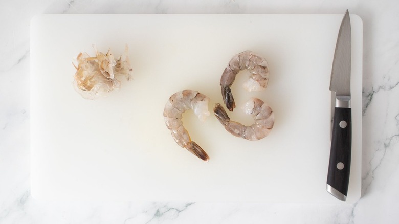 Large raw shrimp on cutting board with knife