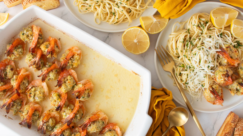 Stuffed shrimp scampi in baking dish next to plate with scampi and pasta