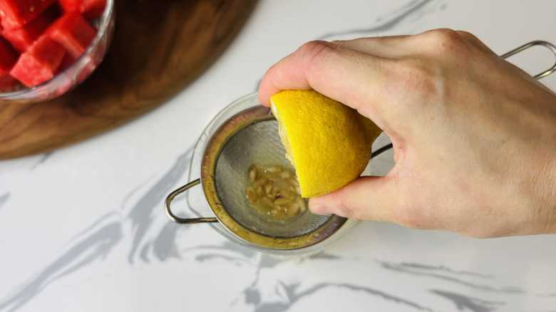 hand juicing lemon over strainer