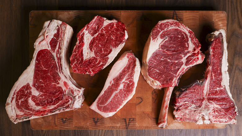 Various raw steaks on a wood cutting board