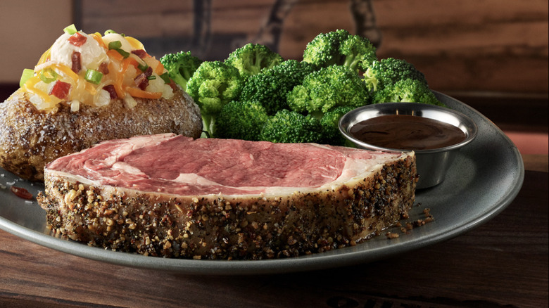 Outback Steakhouse prime rib with loaded baked potato, broccoli, and a cup of au jus