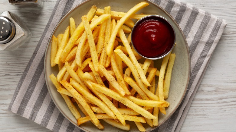 Overhead shot of french fries on a plate with ketchup