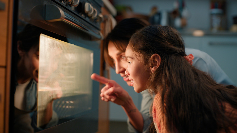 Mom and daughter looking at an item baking in the oven