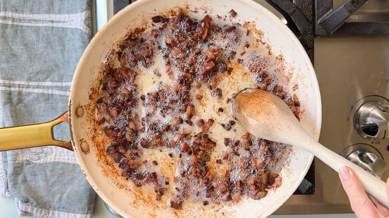 Cooking diced bacon in skillet on stovetop