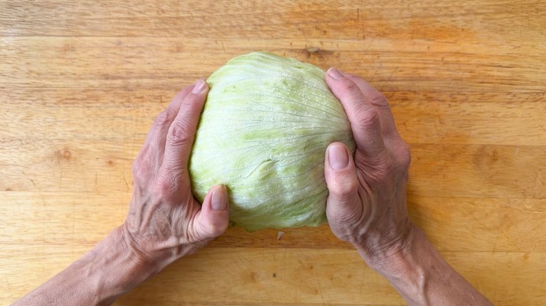 Striking a head of iceberg lettuce on a cutting board to loosen the core