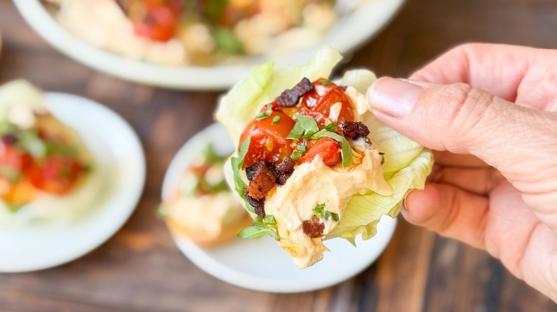 Holding a lettuce cup filled with over-the-top BLT dip
