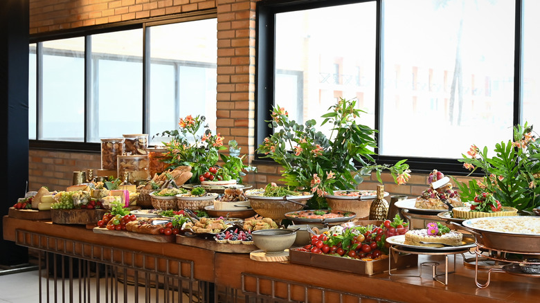 Buffet table covered in dishes of food and vases of flowers
