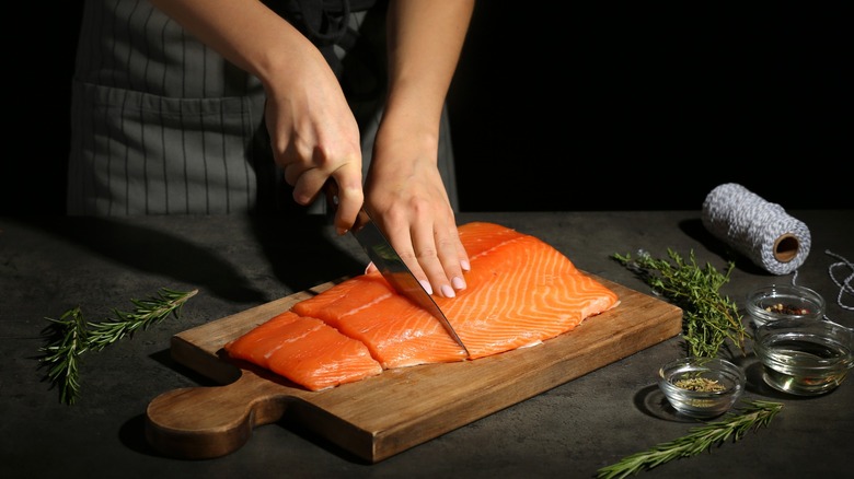 a chef slicing raw salmon filet into several portions