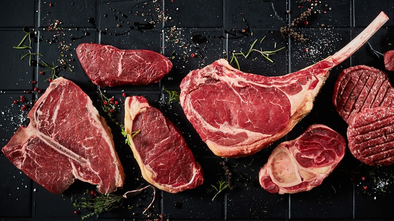 various raw steaks with herbs
