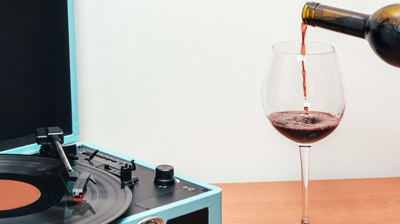 wine pouring into glass next to vinyl player