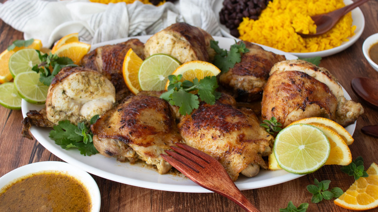 Mojo chicken on platter with citrus slices and herbs