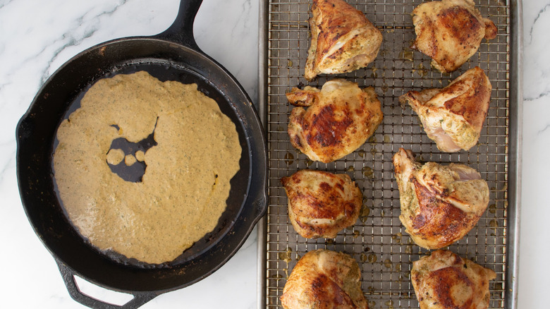 Marinade in skillet next to seared chicken pieces on wire rack
