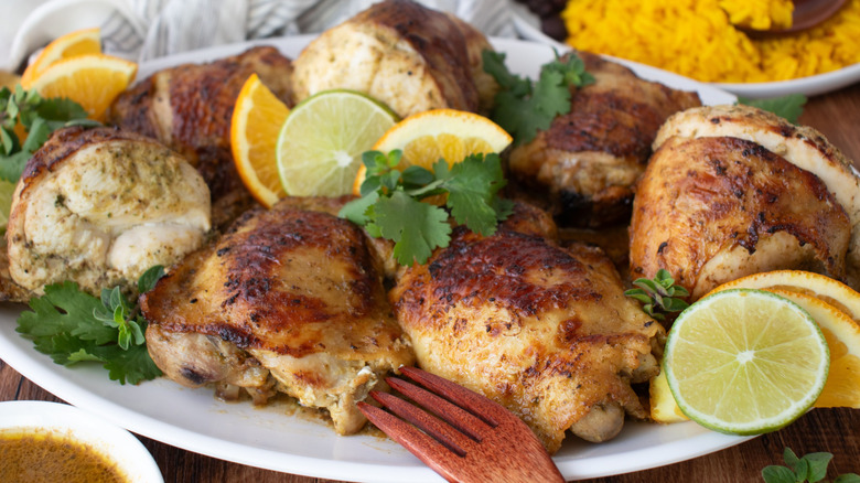 Mojo chicken on platter with citrus slices and cilantro