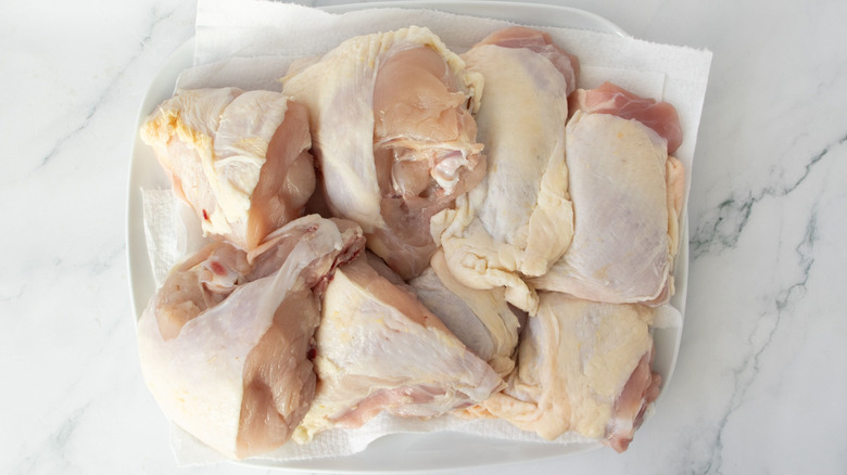 Raw chicken pieces sitting on paper towel-lined plate