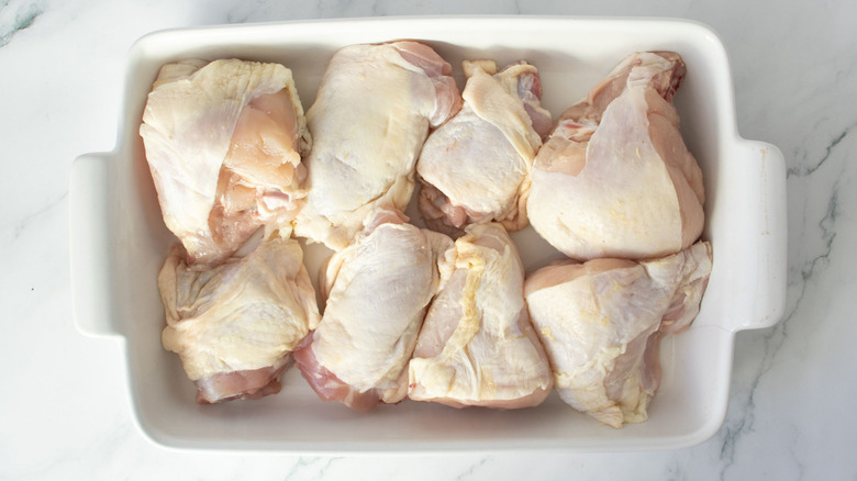 Raw chicken pieces in casserole dish