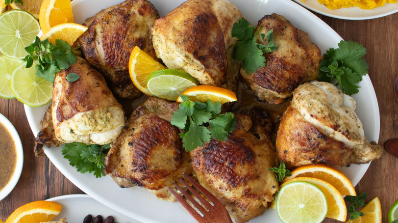 Mojo chicken on platter with citrus slices and herbs