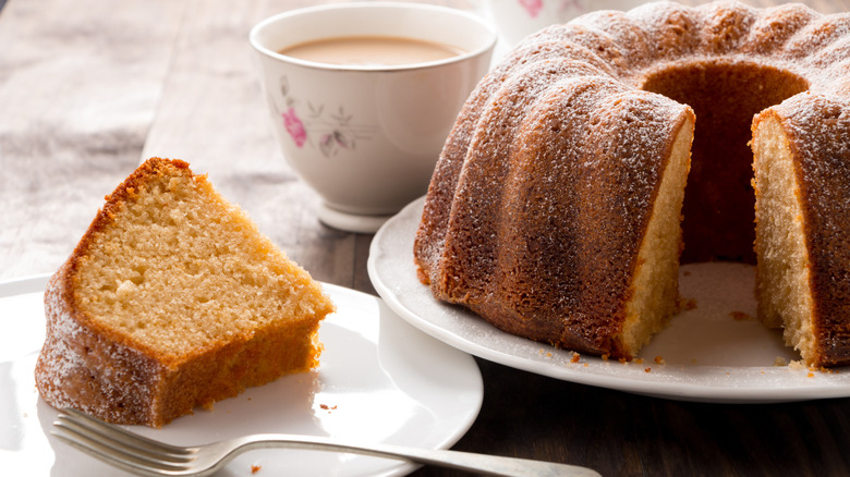 Bundt cake with a slice on a plate with a fork, a cup of tea in the background