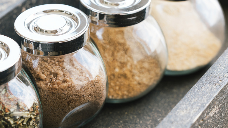 Close up of glass spice containers with wooden lip on a shelf