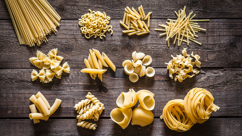Several pasta shapes photographed from overhead on a wooden table.