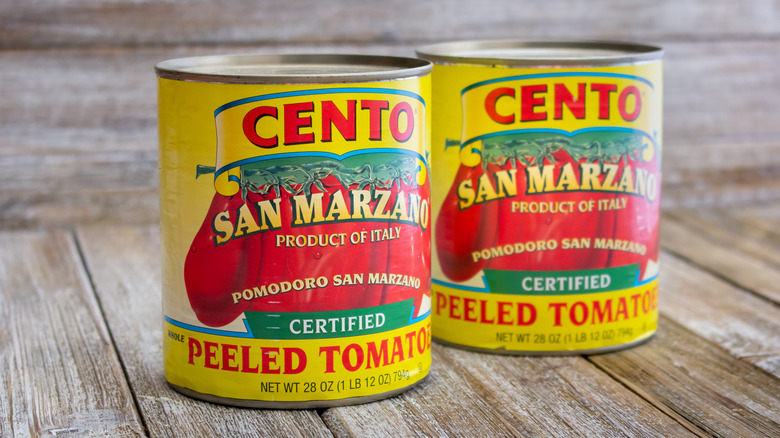 Two cans of San Marzano tomatoes on a wooden background.