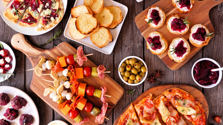 Various platters and wooden boards filled with appetizers sitting on a wooden table