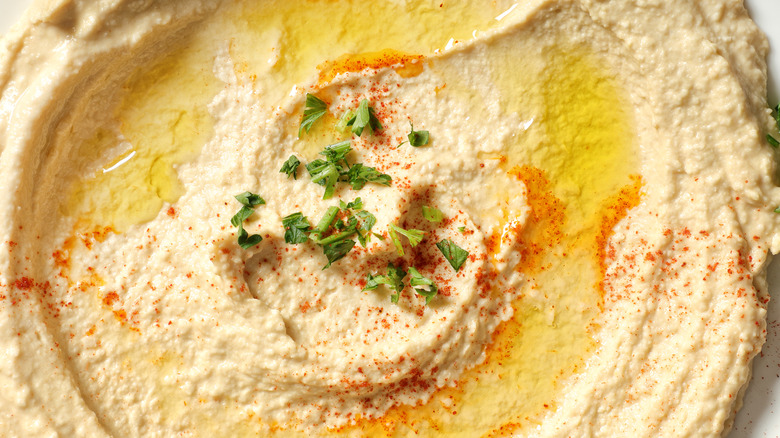 Close-up of humus topped with olive oil, seasoning, and parsley
