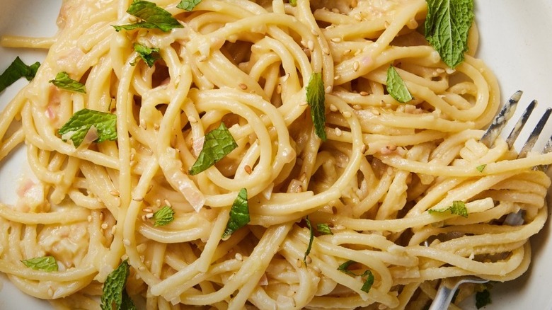 Hummus-coated pasta topped with sesame seeds and basil