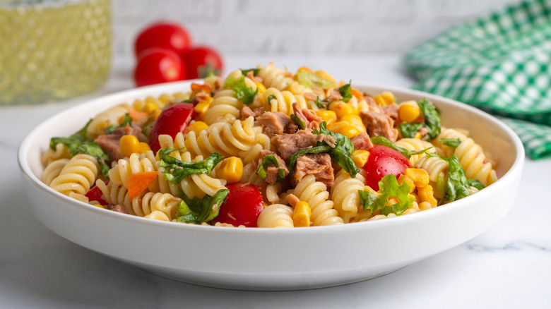 Pasta salad with herbs and veggies in white bowl