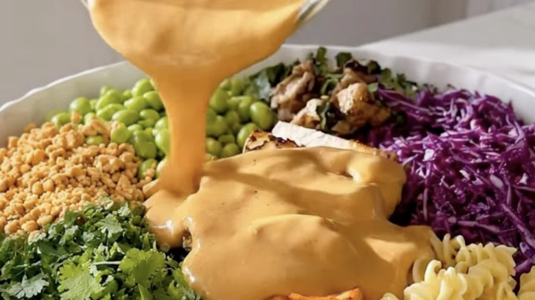 cremay peanut dressing pouring over a salad