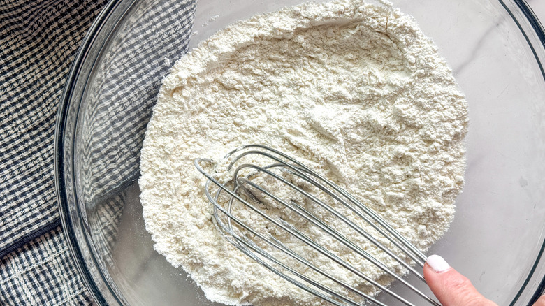 hand whisking flour in bowl
