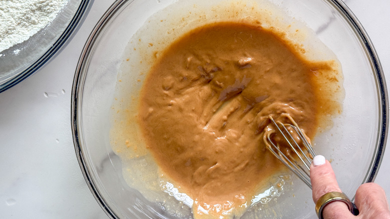 hand whisking peanut butter in bowl