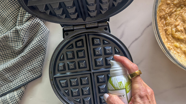 hand spraying waffle maker with cooking spray