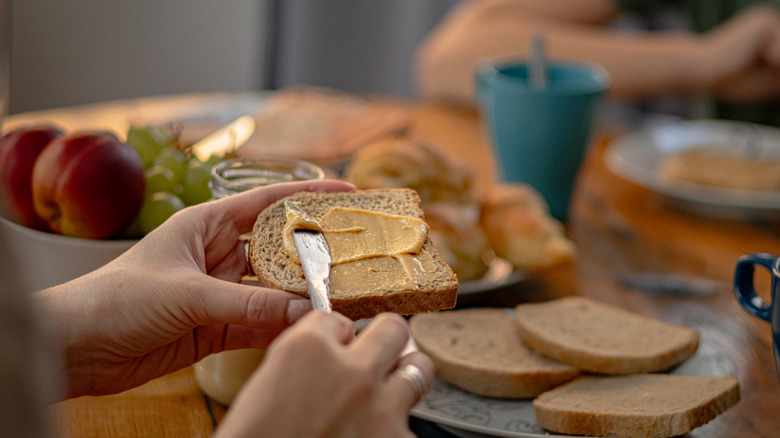 peanut butter being spread on wheat toast