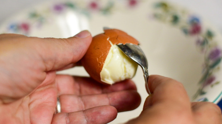 Peeling a hard-boiled egg with spoon
