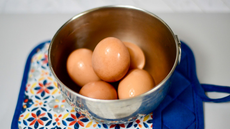 A metal bowl filled with brown eggs