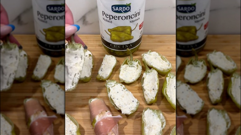 Pepperoncini pepper halves stuffed with cream cheese sitting on a wooden cutting board