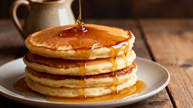 Stack of pancakes with syrup dripping over them.