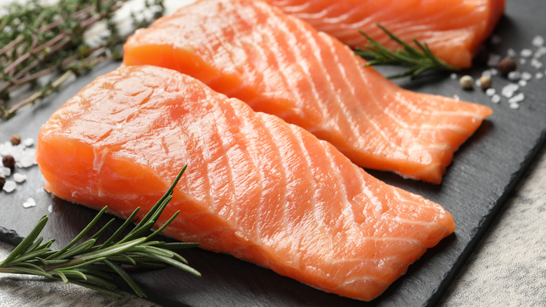 Uncooked salmon fillets on a stone board.