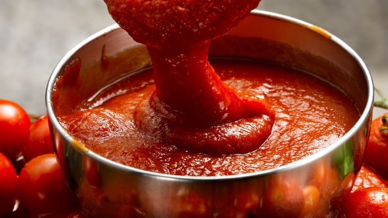 A large sliver bowl of tomato sauce.