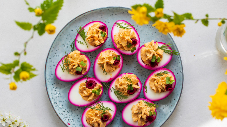 pink pickled and deviled eggs on a speckled blue plate